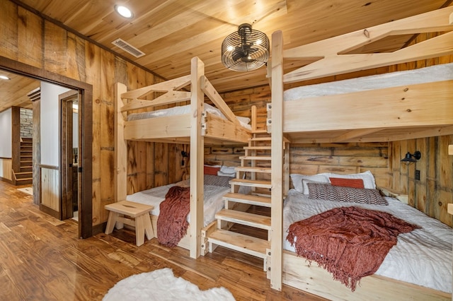 bedroom with visible vents, wood finished floors, wood ceiling, and wood walls