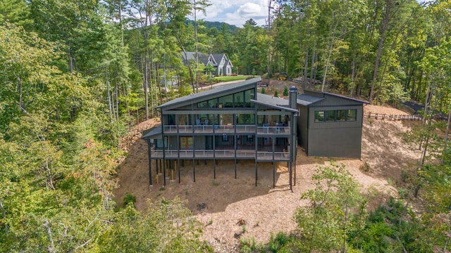 rear view of house featuring a wooded view and a wooden deck