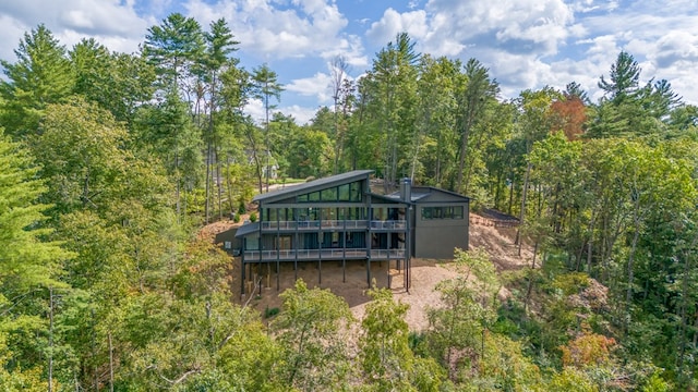 rear view of property featuring a wooded view and a wooden deck