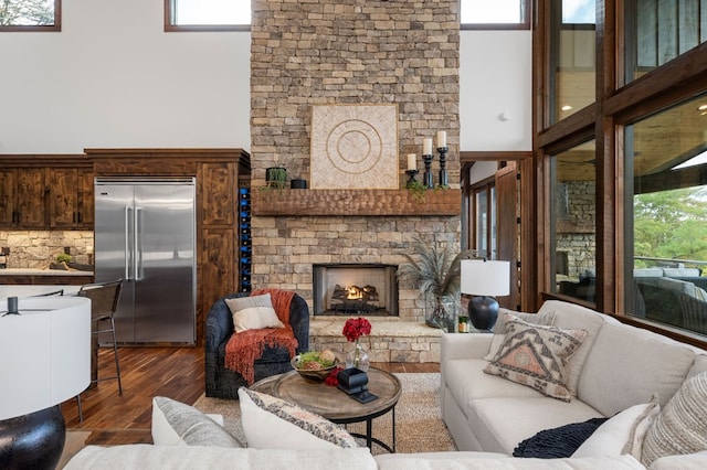 living area with a high ceiling, a lit fireplace, and wood finished floors