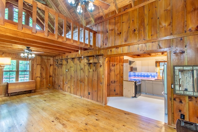 unfurnished room featuring high vaulted ceiling, wooden walls, and light hardwood / wood-style floors