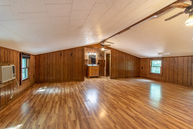 bonus room featuring ceiling fan, lofted ceiling, wooden walls, and light hardwood / wood-style floors