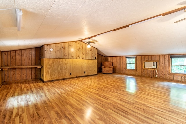 bonus room with vaulted ceiling, a healthy amount of sunlight, a wall mounted air conditioner, and light hardwood / wood-style floors