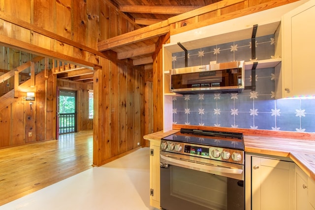 kitchen with white cabinetry, ventilation hood, wooden walls, and stainless steel range oven