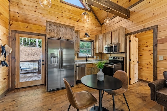 kitchen with hardwood / wood-style flooring, stainless steel appliances, wood walls, a sink, and beamed ceiling