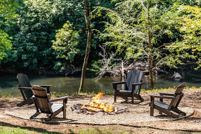 surrounding community with a fire pit and a water view