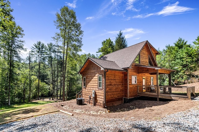 view of side of property featuring central AC unit and roof with shingles