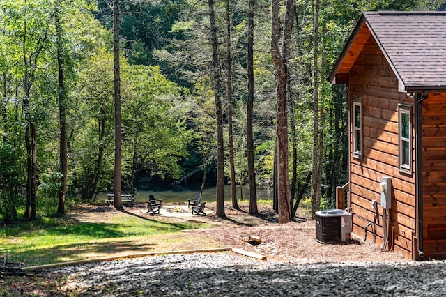 view of yard featuring a forest view, a fire pit, and central AC