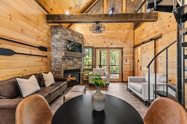 living area featuring beamed ceiling, wooden walls, and a barn door