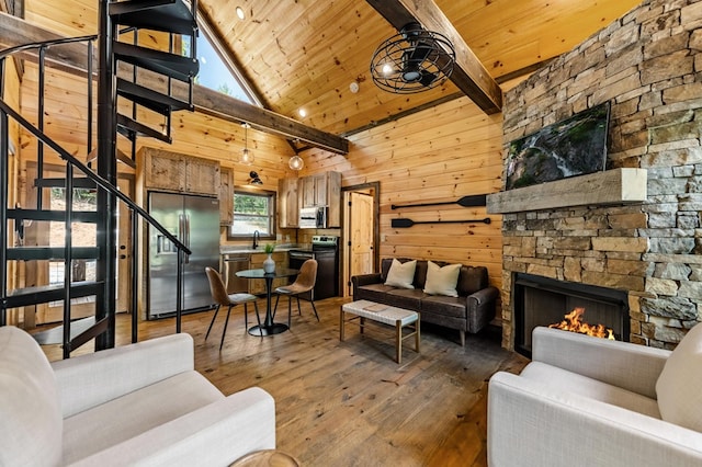 living area with wood-type flooring, wood ceiling, wood walls, a stone fireplace, and stairs