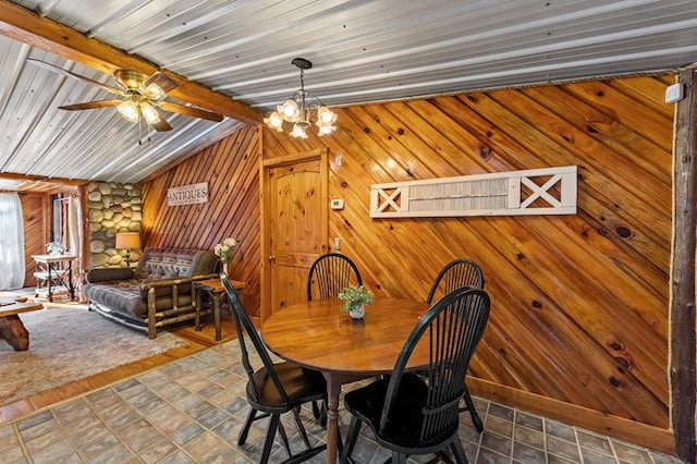 dining room featuring lofted ceiling with beams, ceiling fan with notable chandelier, wooden ceiling, and wooden walls