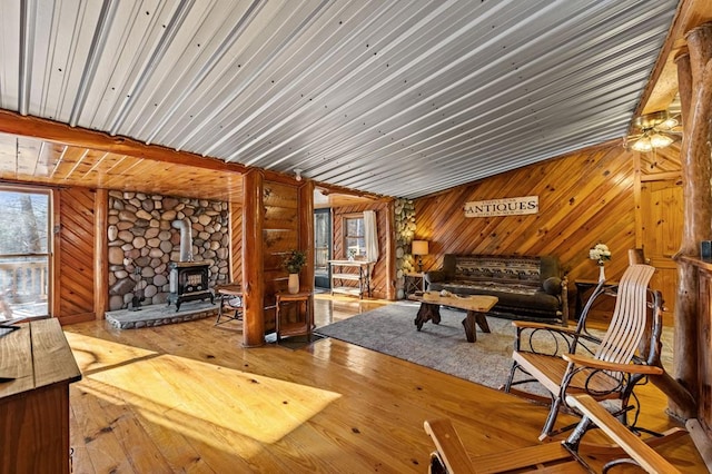 living room featuring wood-type flooring, wooden walls, and a wood stove