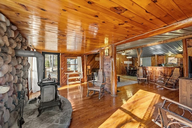 living room featuring wood-type flooring, a wood stove, wood ceiling, and wooden walls