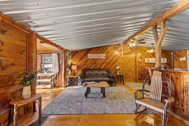 living area with hardwood / wood-style flooring, lofted ceiling, and wood walls