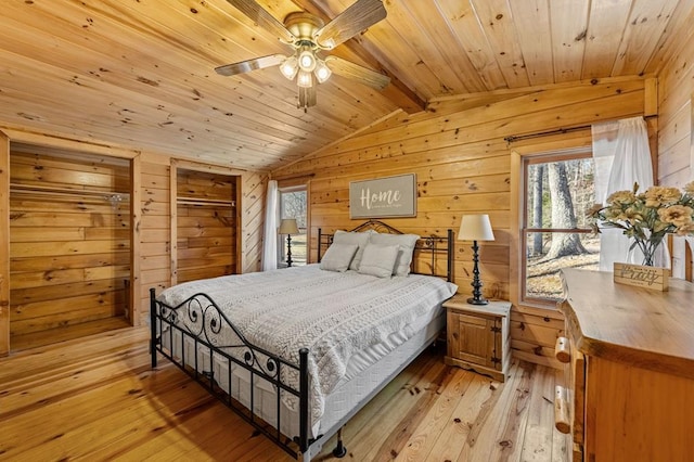 bedroom featuring lofted ceiling with beams, wood ceiling, wooden walls, and light hardwood / wood-style floors