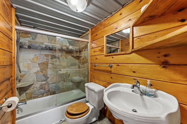 full bathroom with enclosed tub / shower combo, sink, toilet, and wood walls