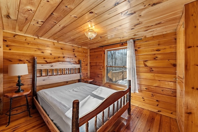 bedroom with wood-type flooring, wooden walls, and wooden ceiling