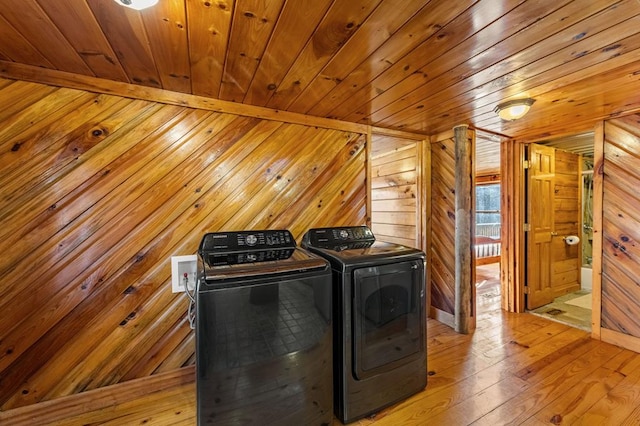 clothes washing area featuring wooden ceiling, light hardwood / wood-style floors, washing machine and dryer, and wood walls