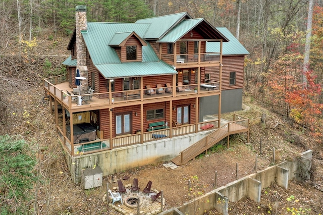 back of property with french doors, a balcony, a deck, and a fire pit