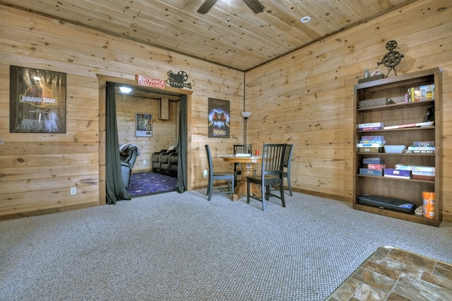 dining space with wood ceiling, wooden walls, ceiling fan, and carpet flooring