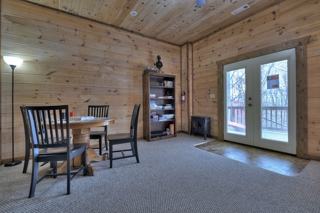 carpeted dining room featuring wood walls, wood ceiling, and french doors