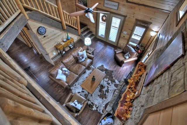 unfurnished living room with ceiling fan, a towering ceiling, and wooden walls