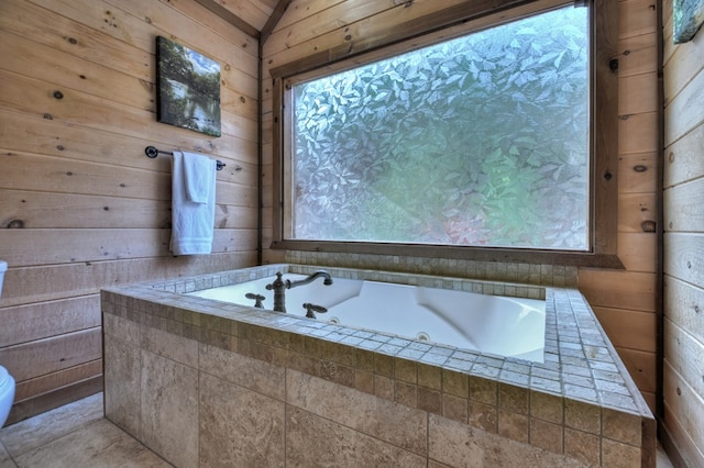 bathroom with a relaxing tiled tub, vaulted ceiling, and wood walls