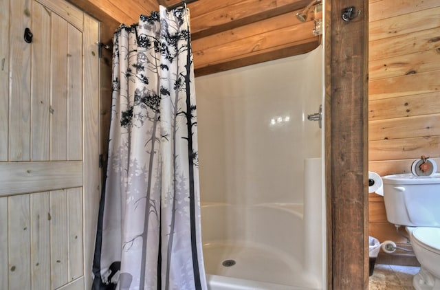 bathroom with a shower with curtain, toilet, and wood walls