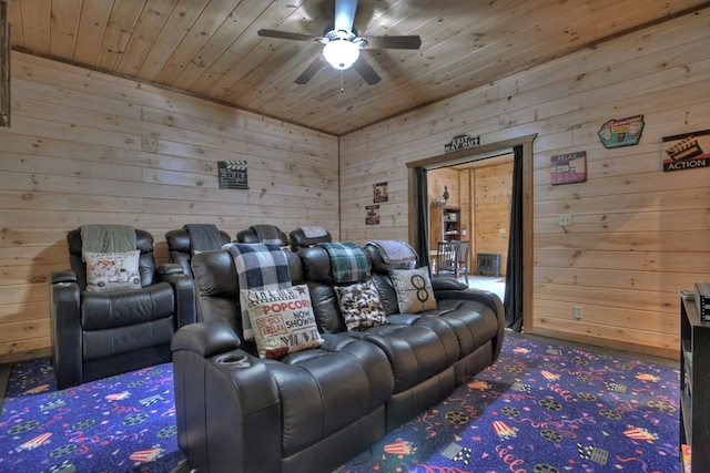 carpeted home theater with wooden ceiling, ceiling fan, and wood walls