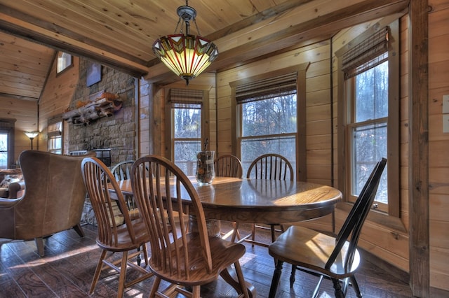 dining space with wood walls, wooden ceiling, a stone fireplace, vaulted ceiling, and dark hardwood / wood-style floors