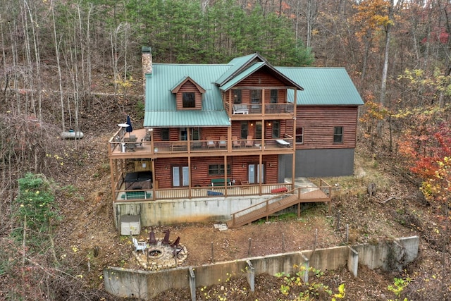 back of property with a wooden deck and a balcony