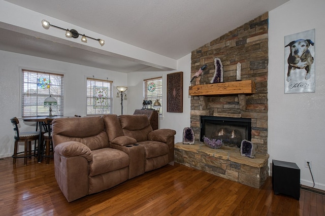 living area featuring baseboards, vaulted ceiling, a fireplace, hardwood / wood-style flooring, and a textured ceiling