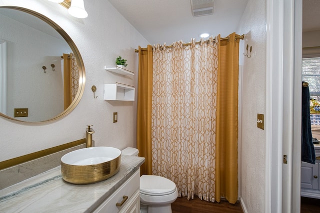 full bathroom featuring vanity, visible vents, curtained shower, toilet, and a textured wall