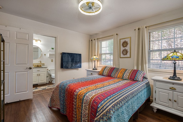 bedroom with connected bathroom and dark wood-style flooring