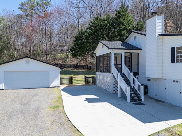 view of front facade with fence, roof with shingles, an outdoor structure, a sunroom, and a garage