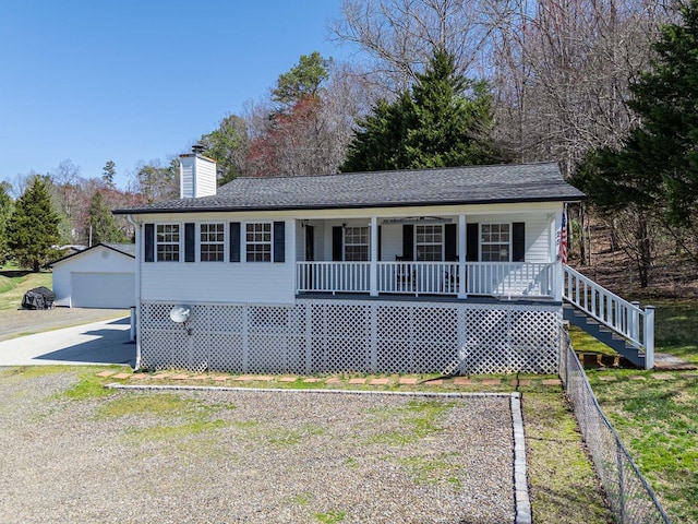 view of front of home with an outbuilding, covered porch, a chimney, and roof with shingles