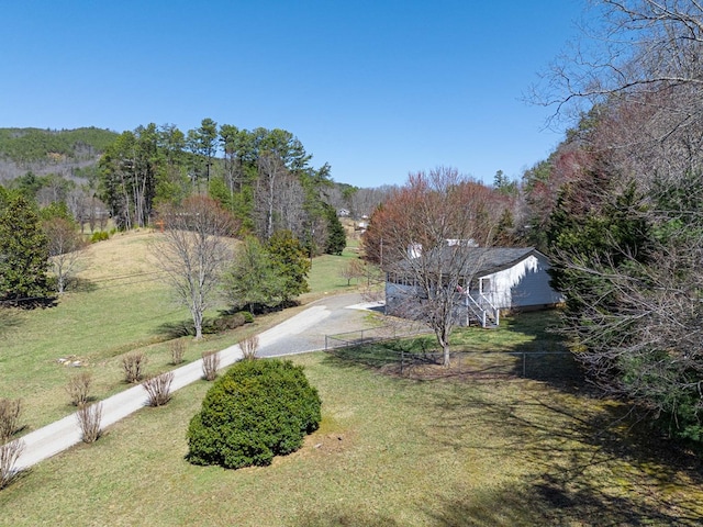 view of yard with stairs, a forest view, and driveway