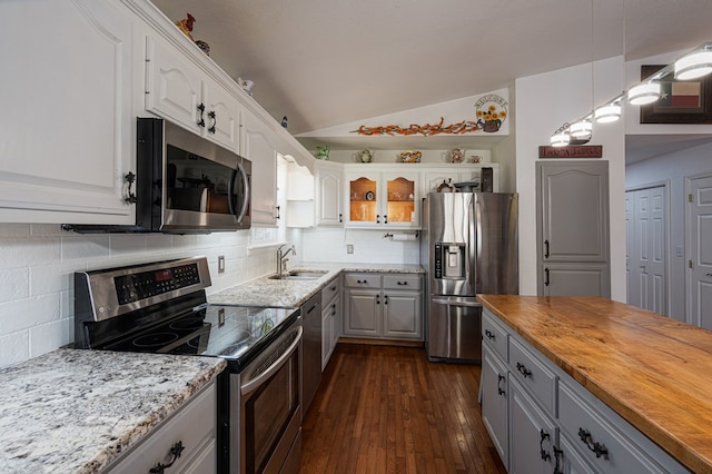 kitchen with dark wood finished floors, a sink, gray cabinetry, stainless steel appliances, and wood counters