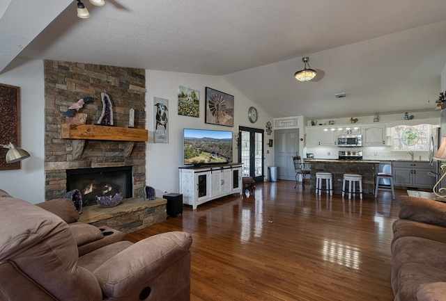 living room featuring dark wood-style floors, a fireplace, and vaulted ceiling