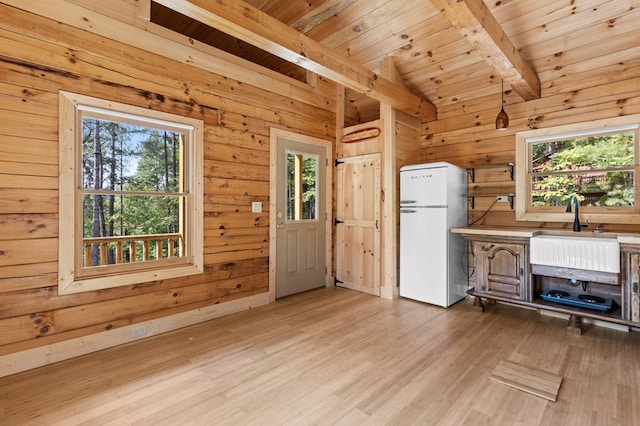 interior space with wooden ceiling, wood walls, white refrigerator, and light hardwood / wood-style floors