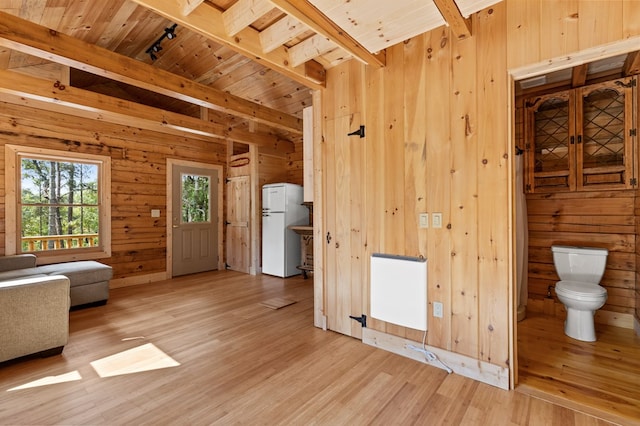 unfurnished living room with light hardwood / wood-style flooring, wooden walls, beamed ceiling, and wooden ceiling