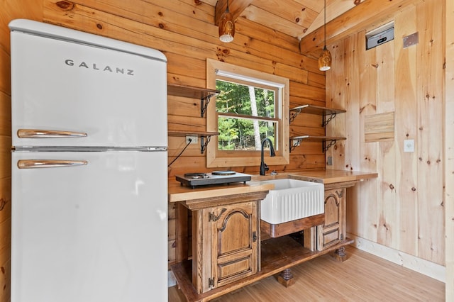 interior space featuring beamed ceiling, decorative light fixtures, wooden walls, light hardwood / wood-style flooring, and white fridge