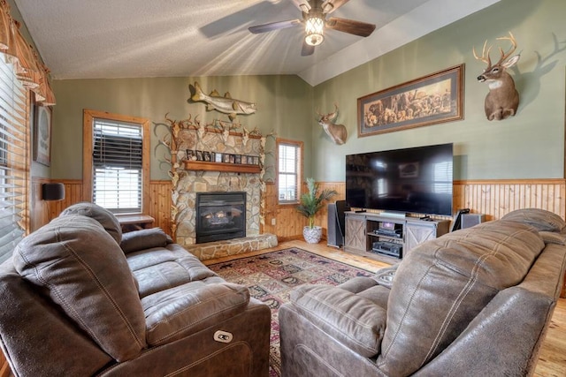 living room with a wainscoted wall, lofted ceiling, ceiling fan, a textured ceiling, and wood finished floors