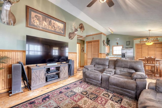 living room with lofted ceiling, a wainscoted wall, wood finished floors, and wood walls