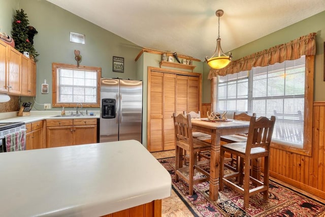 kitchen with a wainscoted wall, a sink, vaulted ceiling, light countertops, and stainless steel refrigerator with ice dispenser