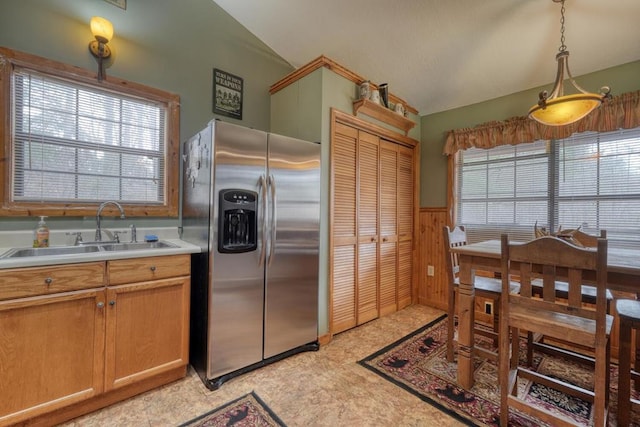 kitchen featuring a wealth of natural light, a wainscoted wall, vaulted ceiling, stainless steel refrigerator with ice dispenser, and a sink