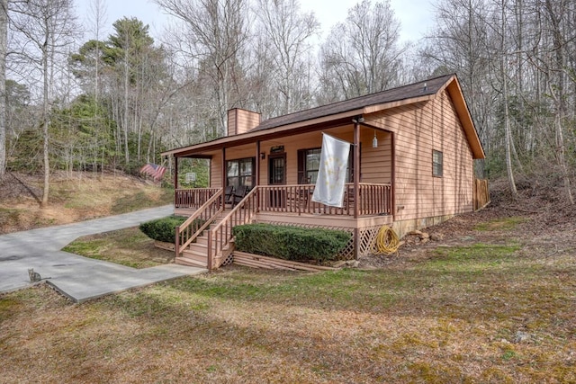 view of front facade featuring covered porch and a chimney