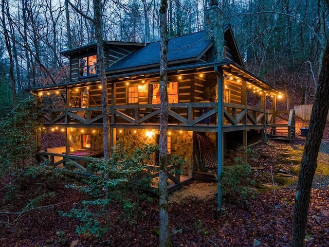 back of house featuring a deck and roof with shingles