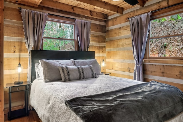 bedroom with beam ceiling, wood walls, and wood ceiling