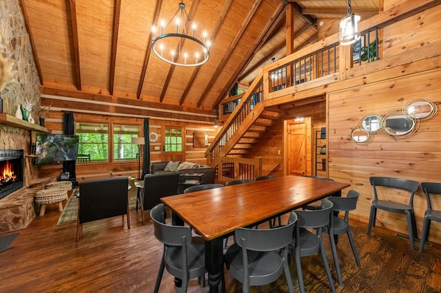 dining room with wood ceiling, beamed ceiling, wood finished floors, stairs, and a stone fireplace